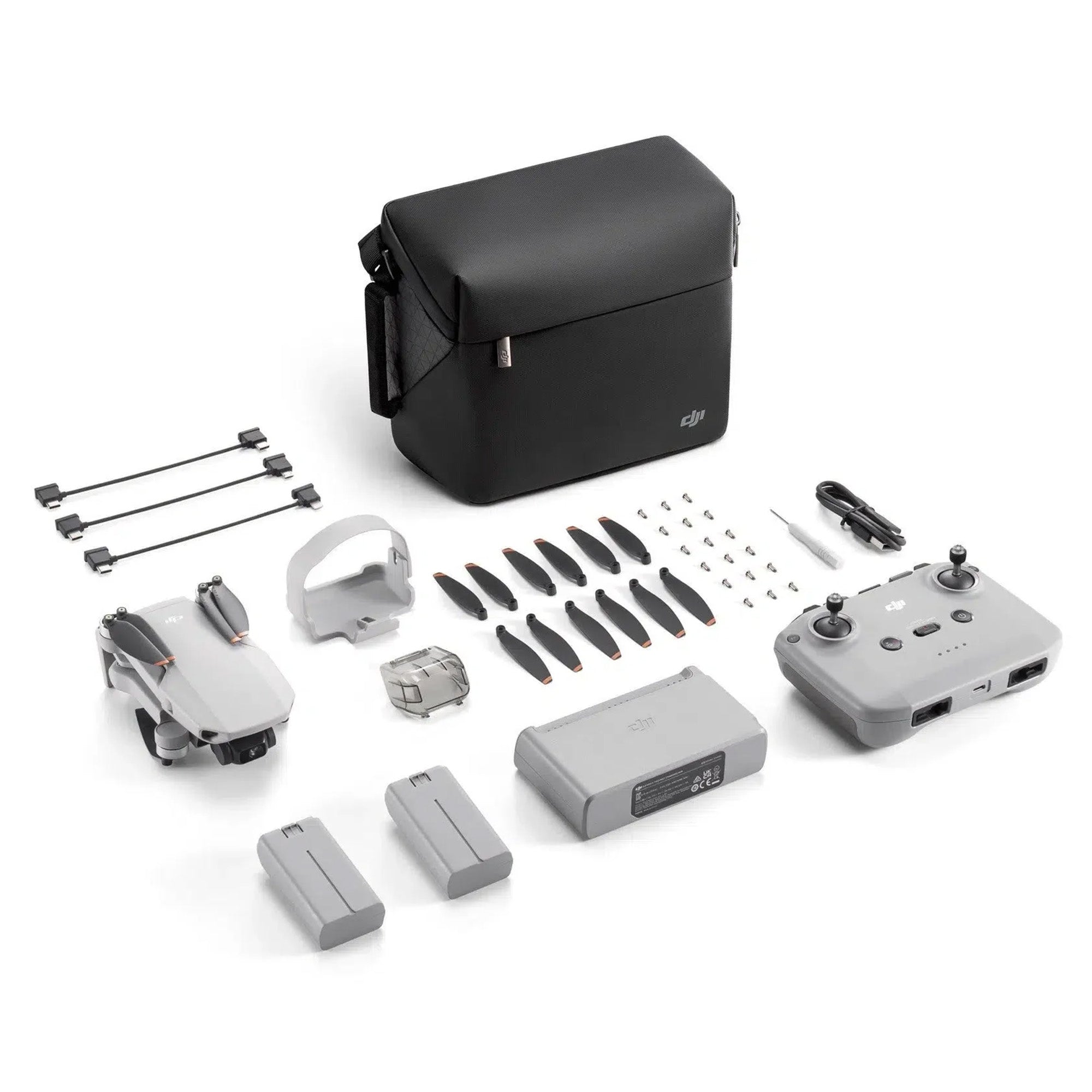 The DJI Mini 4K Drone With RC-N1 Controller in grey on a white background, drone is in it's folded position. Image shows other items that are included with the drone: Gimbal Protector, Spare Propellers, Screwdriver, Screws, DJI RC-N1 RC Cable (USB-C Connector), DJI RC-N1 RC Cable (Lightning Connector), and DJI RC-N1 RC Cable (Standard Micro-USB Connector).